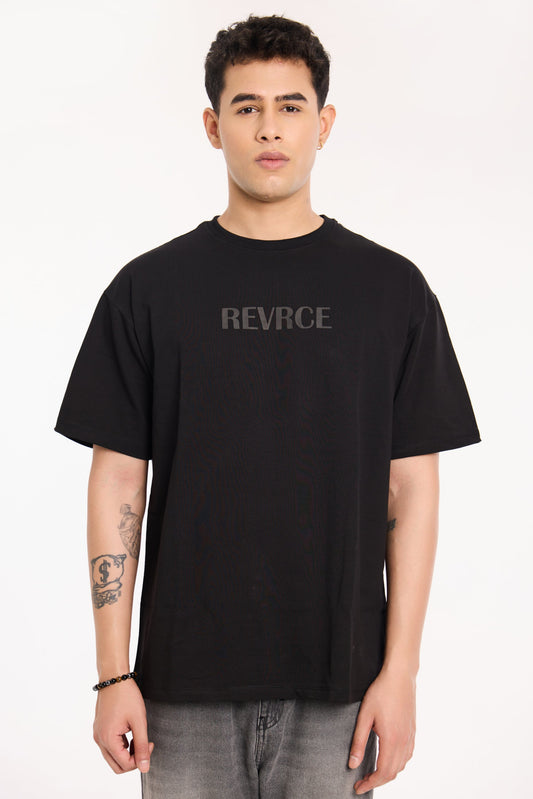 Model wearing Midnight Mark Solid Black Tee by Revrce, oversized fit streetwear T-shirt with front graphic