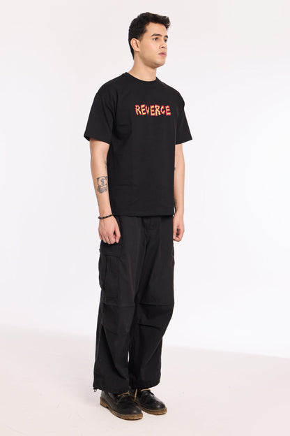 Back view of model wearing Fired Up Black T Shirt by Revrce, oversized streetwear t-shirt